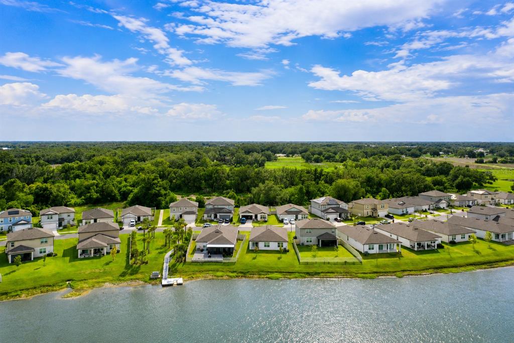 An aerial view shows a row of suburban houses situated along the edge of a lake — 3830 CAPRI COAST DRIVE, PLANT CITY, FL