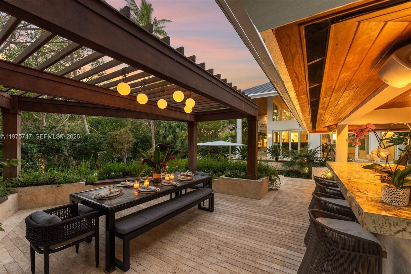 An outdoor patio features a wooden pergola, a dining table with benches, and a bar — 7150 W Lago Dr, Coral Gables FL 33143, CORAL GABLES, FL