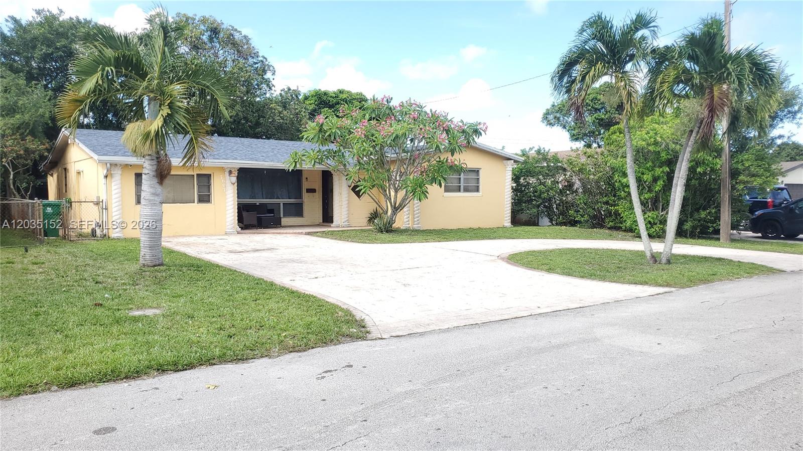 A single-story yellow house features a paved driveway, palm trees, and a front porch — 7607 Dilido Blvd, Miramar FL 33023, MIRAMAR, FL