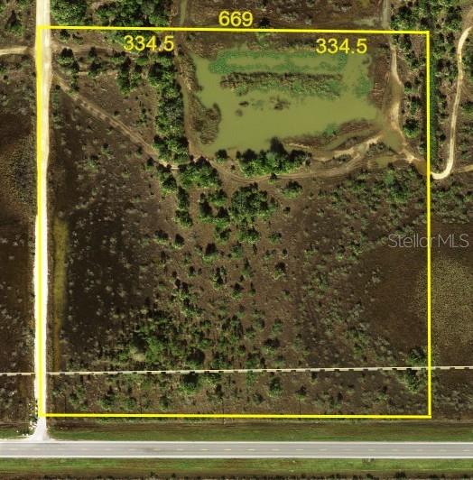 An aerial view shows a rectangular plot of land with a pond and road access — 50690 BERMONT ROAD, PUNTA GORDA, FL
