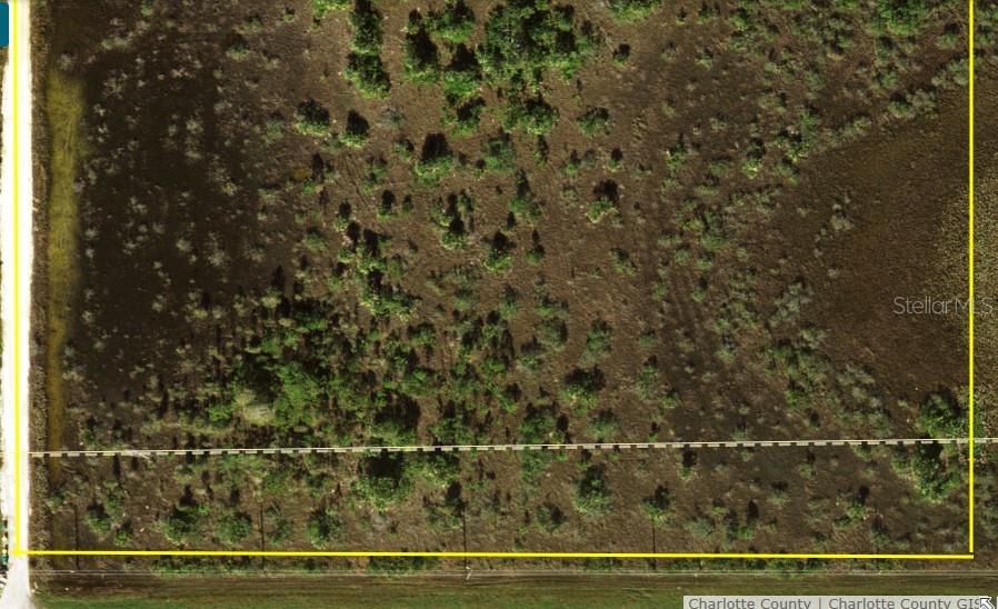 An aerial view of a vacant, undeveloped lot with scattered vegetation and a dirt road — 50690 BERMONT ROAD, PUNTA GORDA, FL