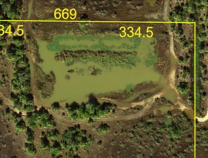An aerial view of a pond with property boundary lines and dimensions overlaid on the landscape — 50690 BERMONT ROAD, PUNTA GORDA, FL