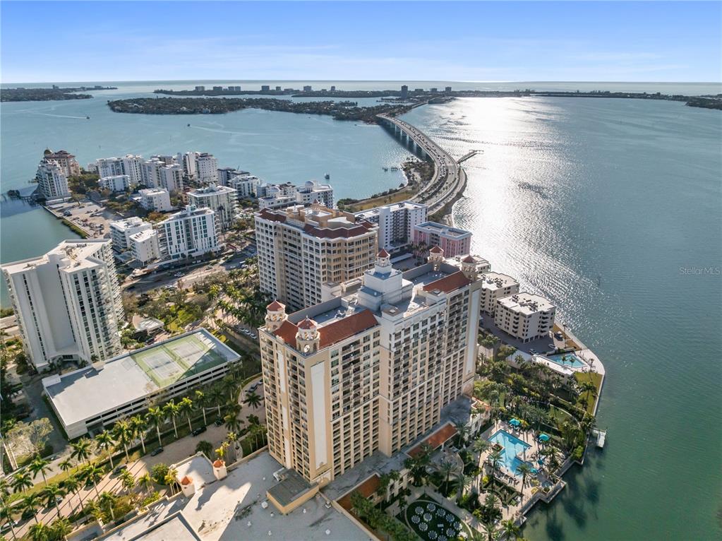 An aerial view shows a large waterfront condominium complex with a pool and tennis courts — 1111 RITZ CARLTON DRIVE UNIT 1603, SARASOTA, FL