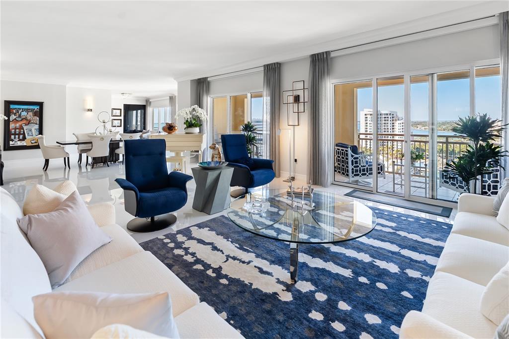 A bright living room features white sofas, blue accent chairs, a glass coffee table, and balcony — 1111 RITZ CARLTON DRIVE UNIT 1603, SARASOTA, FL