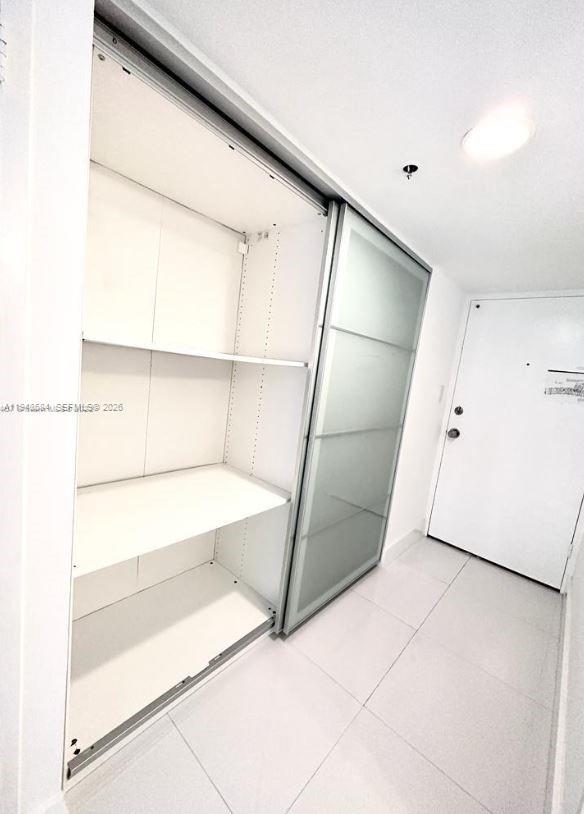 A white closet with open shelving and a sliding frosted glass door in a room — 100 Lincoln Rd # 526, Miami Beach FL 33139, MIAMI BEACH, FL