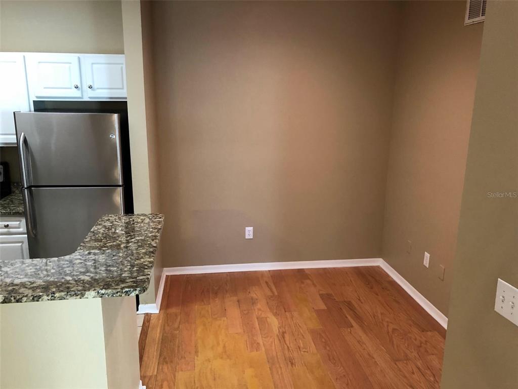 A kitchen dining area features wood flooring, a granite countertop, and a stainless steel refrigerator — 2010 E PALM AVENUE UNIT 15202, TAMPA, FL