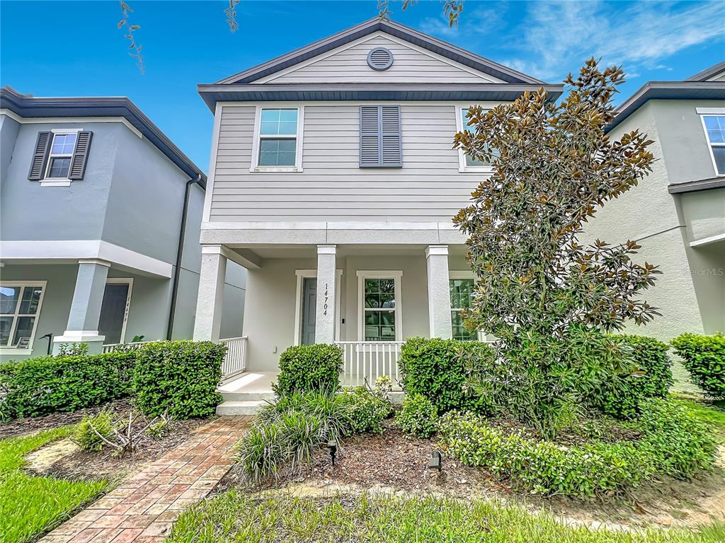 A two-story house with light gray siding, a covered front porch, and manicured landscaping — 14704 SETON CREEK BOULEVARD, WINTER GARDEN, FL