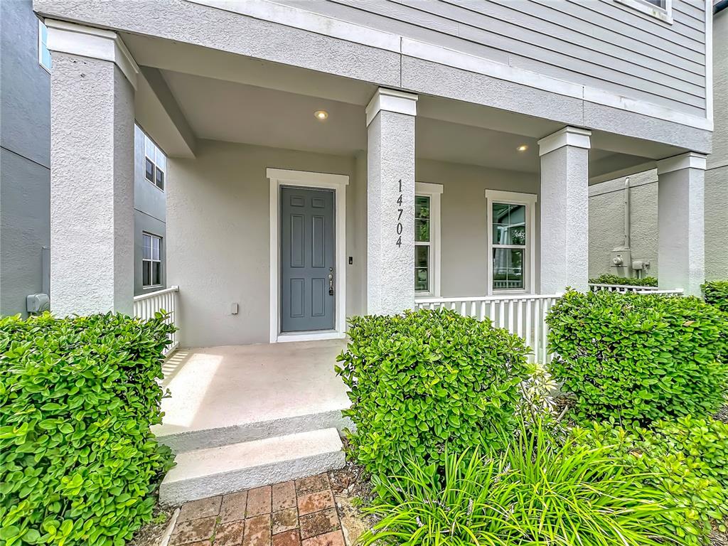 A gray front door is centered on a covered porch with white columns and landscaping — 14704 SETON CREEK BOULEVARD, WINTER GARDEN, FL