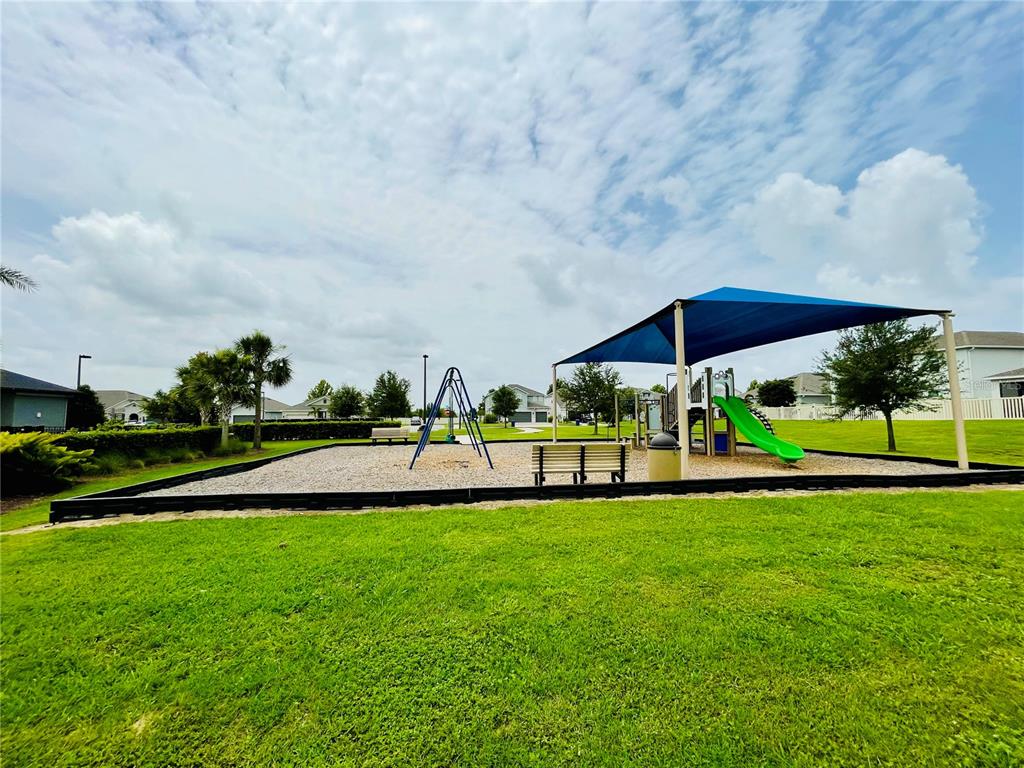 A playground with a swing set, a slide under a blue shade, and benches — 367 LEMONGRASS ROAD, MINNEOLA, FL