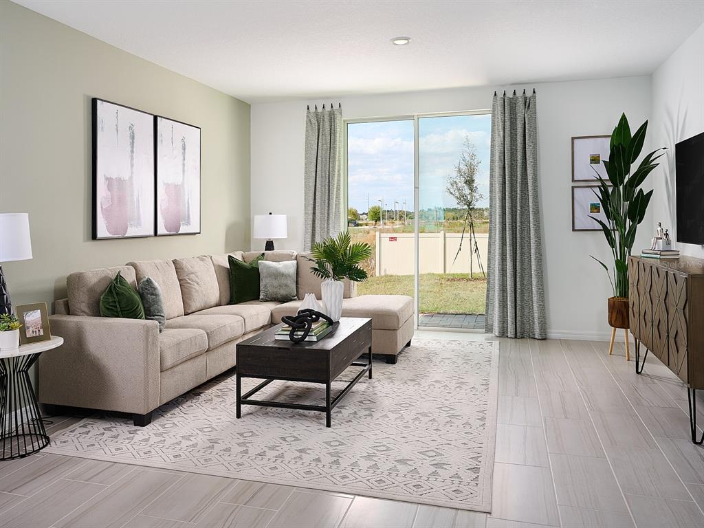 A living room features a beige sectional sofa, a dark coffee table, and a sliding door — 5029 KAIA AVENUE, WINTER HAVEN, FL