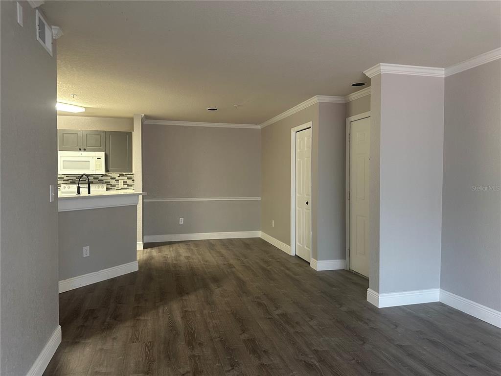 An interior view shows a kitchen with gray cabinets and a living area with wood flooring — 4209 WOODSTORKS WALK WAY UNIT 1205, LUTZ, FL