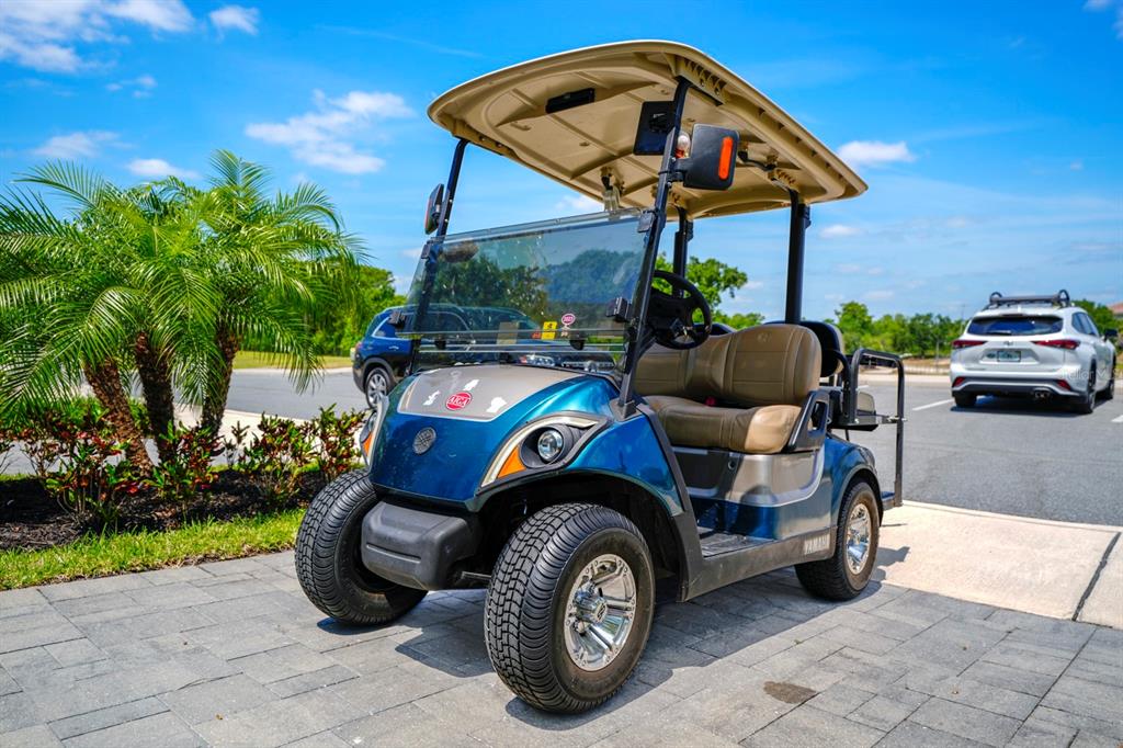 A blue Yamaha golf cart is parked on a paved surface outdoors — 743 DRIVING RANGE COURT, REUNION, FL