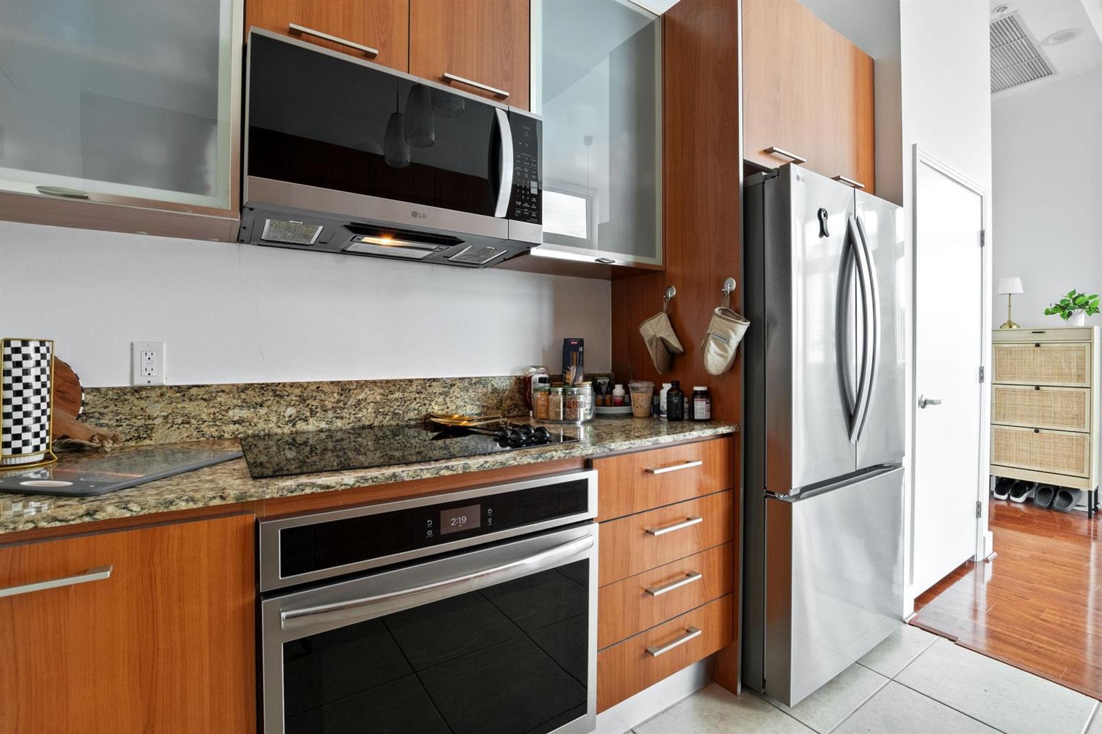 A kitchen features wood cabinets, stainless steel appliances, and granite countertops — 9066 SW 73rd Court # 701, Miami FL 33156, MIAMI, FL