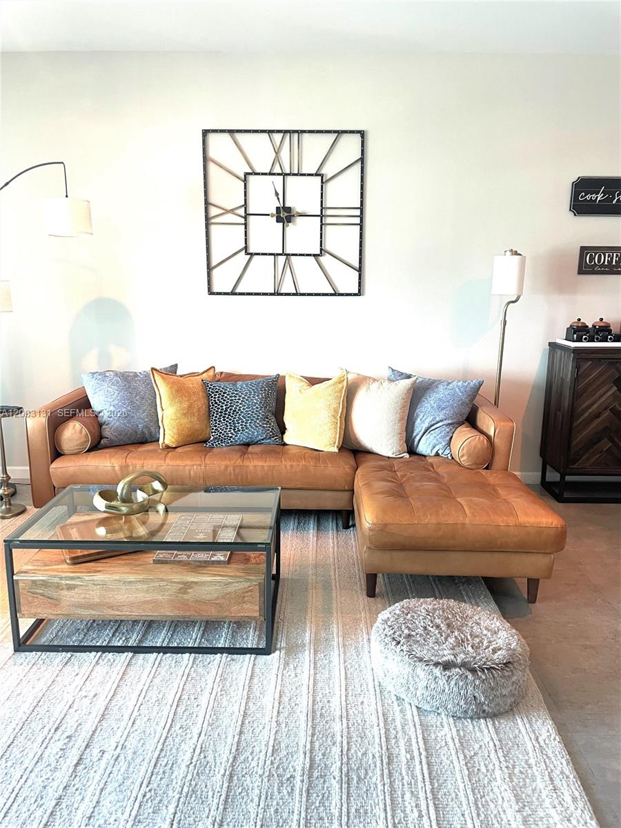 A living room features a tan leather sectional sofa, a glass coffee table, and a wall clock — 888 Biscayne Blvd # 4310, Miami FL 33132, MIAMI, FL