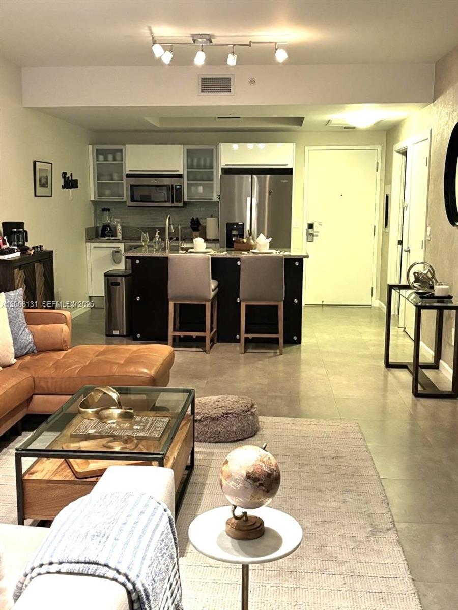 An open-concept living room and kitchen featuring a leather sofa, island seating, and tile flooring — 888 Biscayne Blvd # 4310, Miami FL 33132, MIAMI, FL