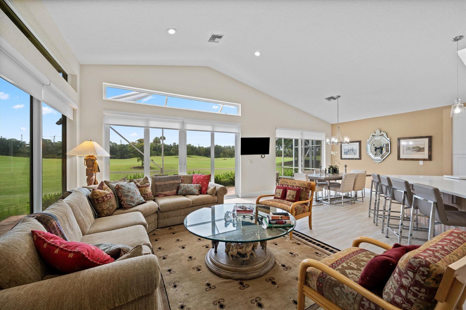 A living and dining area with vaulted ceilings, a glass coffee table, and golf course views — 4706 Carlton Golf Drive, Lake Worth FL 33449, LAKE WORTH, FL