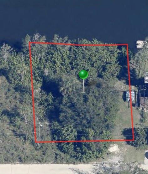 An aerial view shows a rectangular, tree-covered lot outlined in red next to a body of water — 12097 W GULF BREEZE COURT, CRYSTAL RIVER, FL