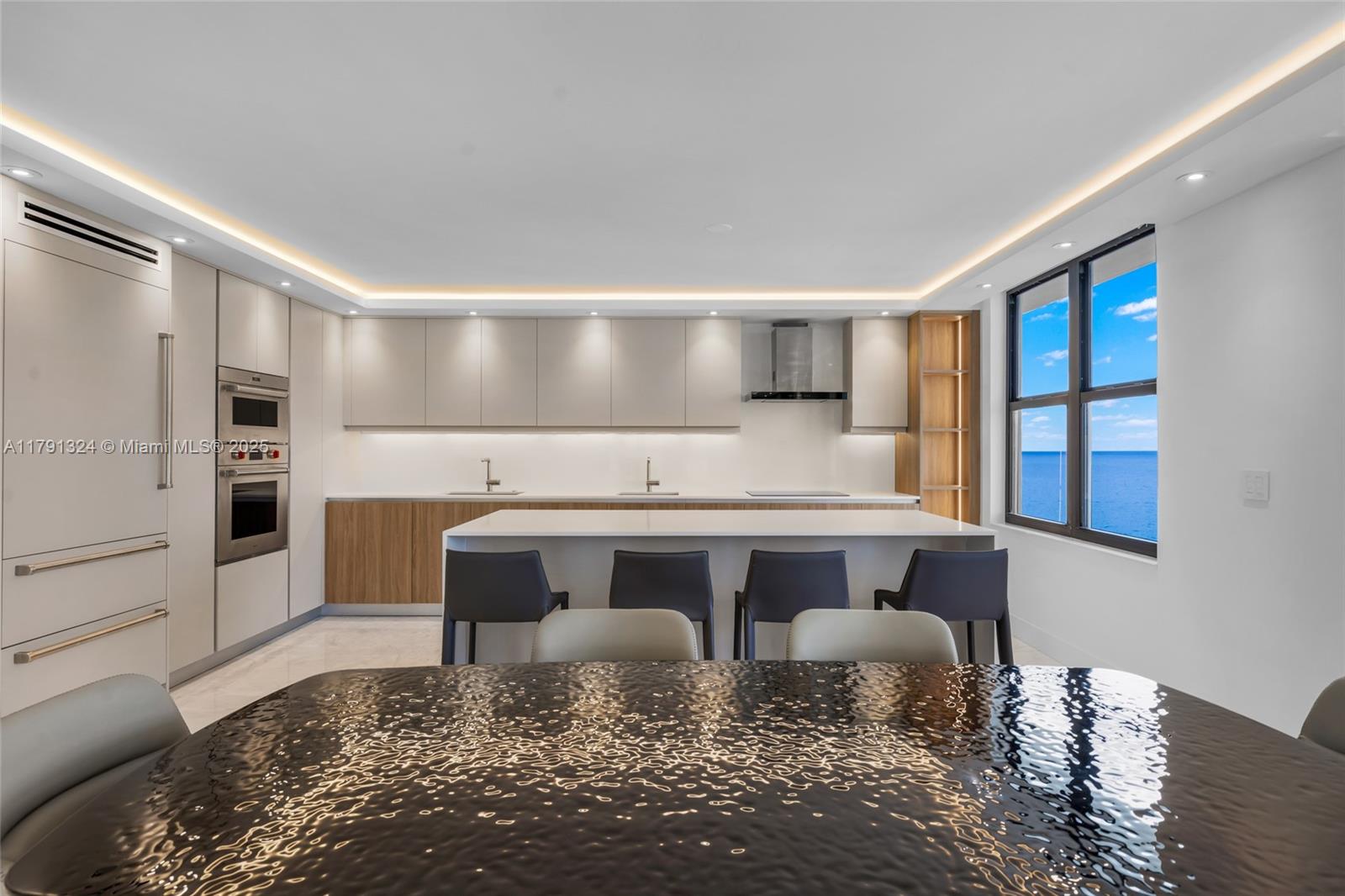 A modern kitchen features light wood cabinets, a white island, and an ocean view window — 9801 Collins Ave # 17R, Bal Harbour FL 33154, BAL HARBOUR, FL