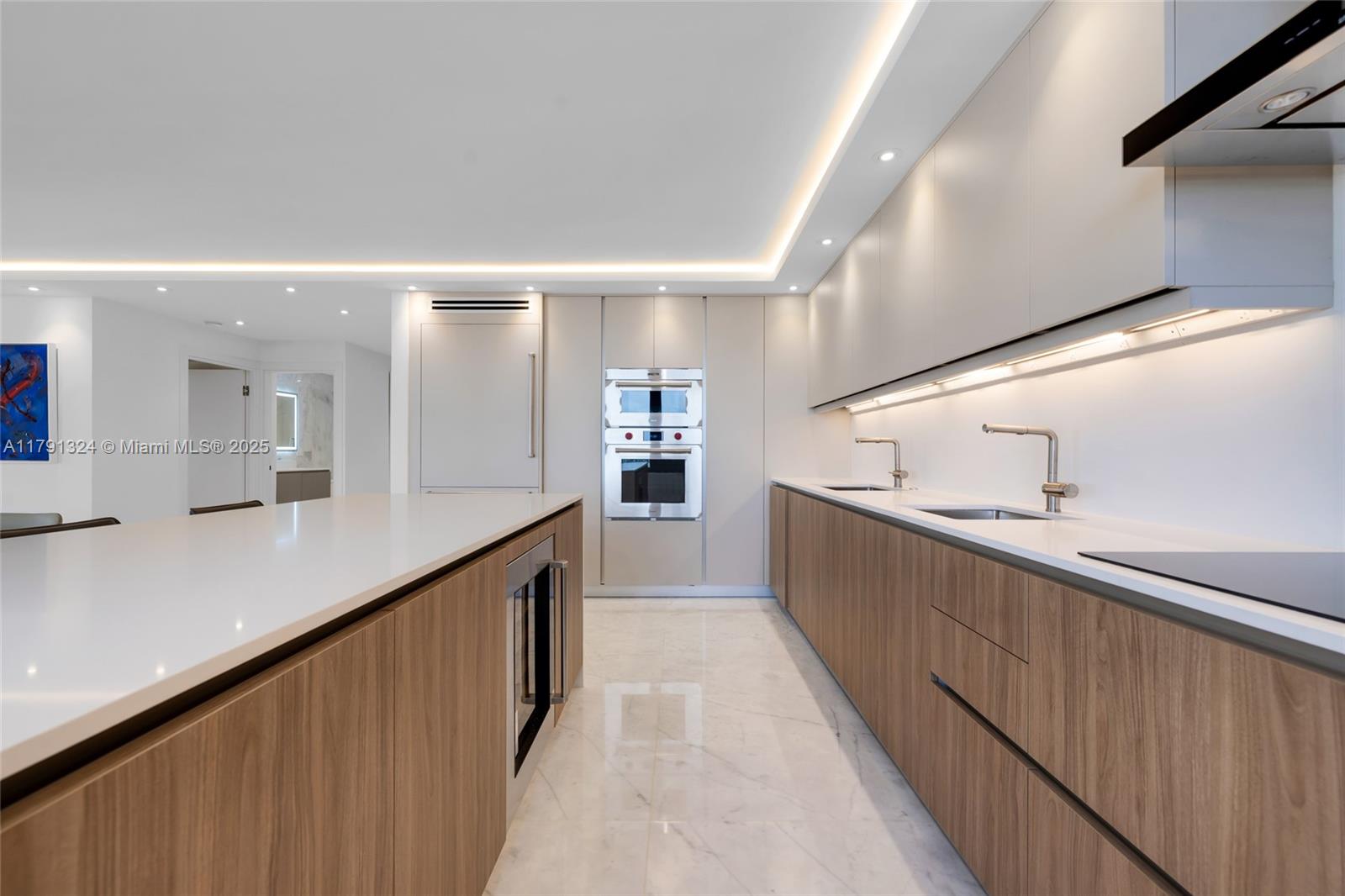 A modern kitchen features wood-grain cabinetry, white countertops, stainless steel appliances, and marble flooring — 9801 Collins Ave # 17R, Bal Harbour FL 33154, BAL HARBOUR, FL