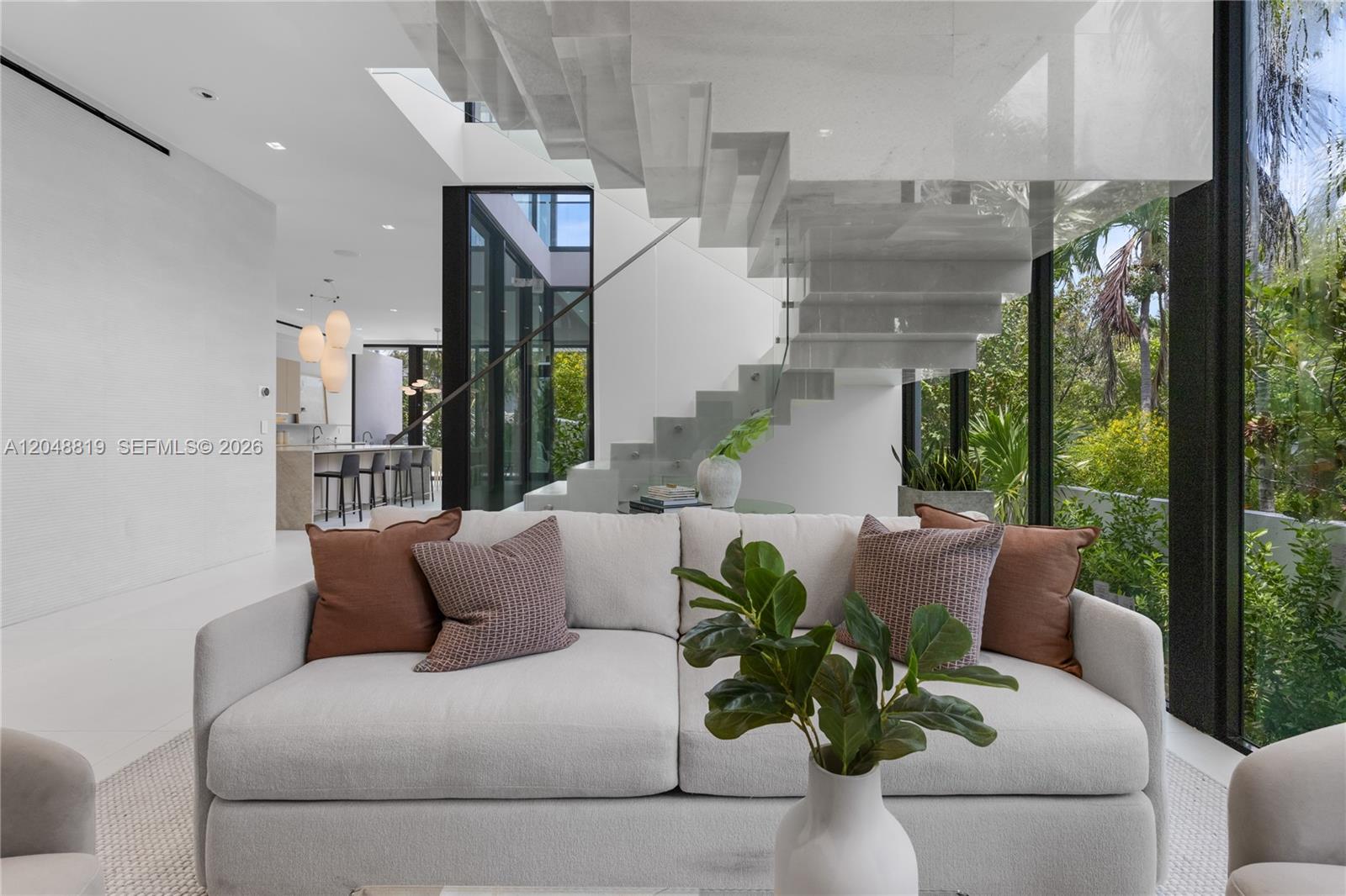 A modern living room features a white sofa, a floating stone staircase, and floor-to-ceiling windows — 4504 Sheridan Ave, Miami Beach FL 33140, MIAMI BEACH, FL