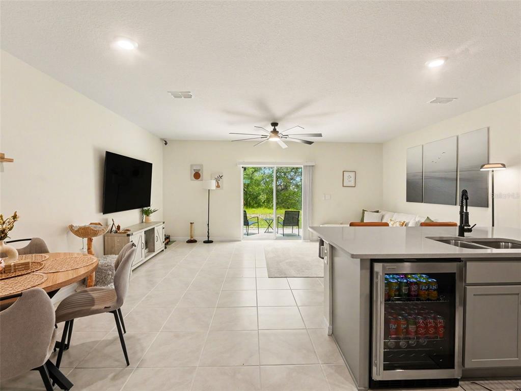 A bright open-concept living area features a kitchen island with a beverage cooler and tile flooring — 2356 PENGUIN BOULEVARD, DAVENPORT, FL