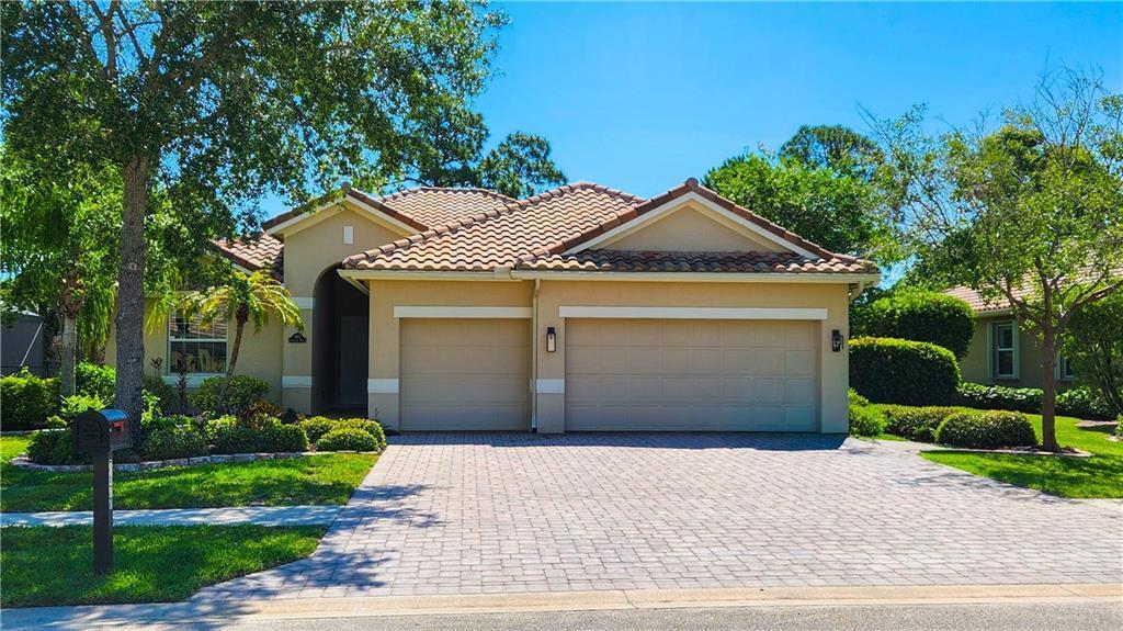 A single-story house with a tan stucco exterior, a tile roof, and a paved driveway — 7677 Fieldstone Ranch Square, Vero Beach FL 32967, VERO BEACH, FL