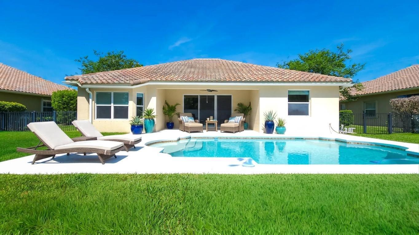 A backyard view of a house with a swimming pool, patio furniture, and lawn — 7677 Fieldstone Ranch Square, Vero Beach FL 32967, VERO BEACH, FL
