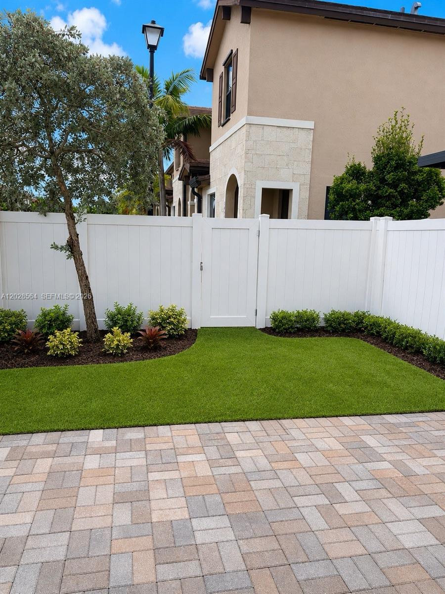 A backyard features a paved patio, a patch of artificial turf, and a white fence — 3368 W 105th Ter, Hialeah FL 33018, HIALEAH, FL
