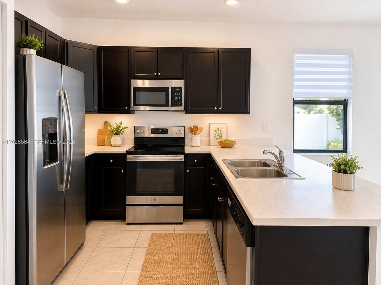A kitchen features dark cabinets, stainless steel appliances, and a light-colored countertop island — 3368 W 105th Ter, Hialeah FL 33018, HIALEAH, FL