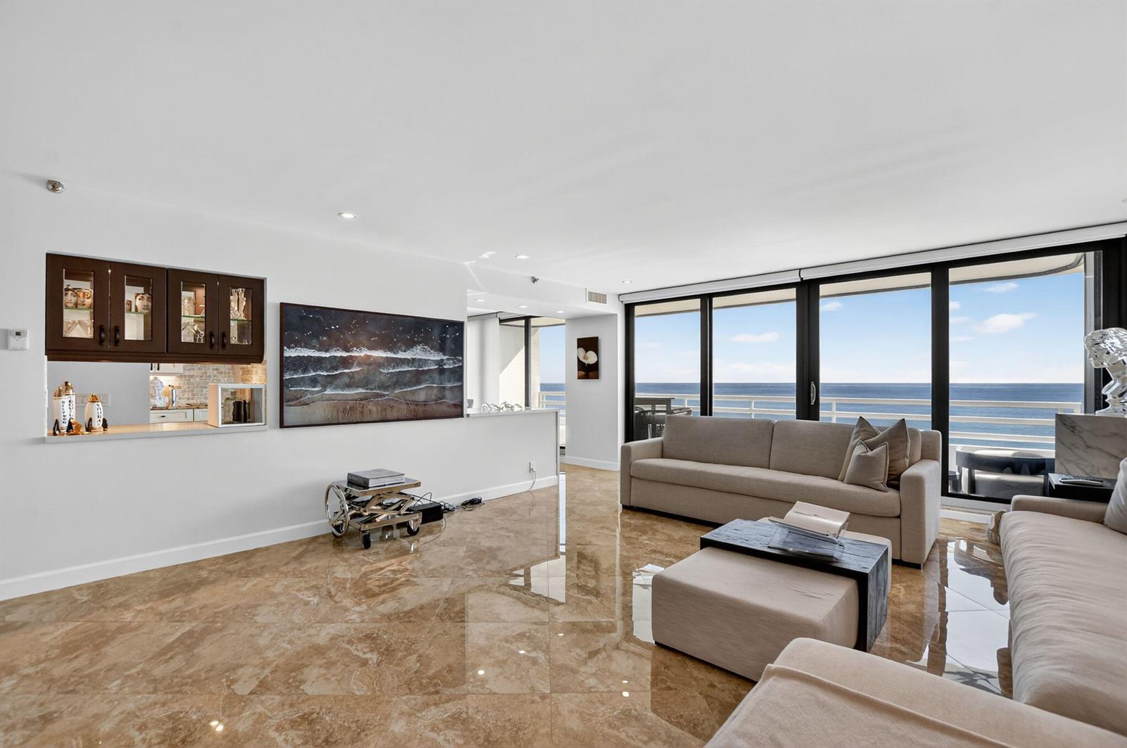A living room with marble floors, a beige sofa, and floor-to-ceiling windows overlooking the ocean — 1500 S Ocean Boulevard # 704, Boca Raton FL 33432, BOCA RATON, FL