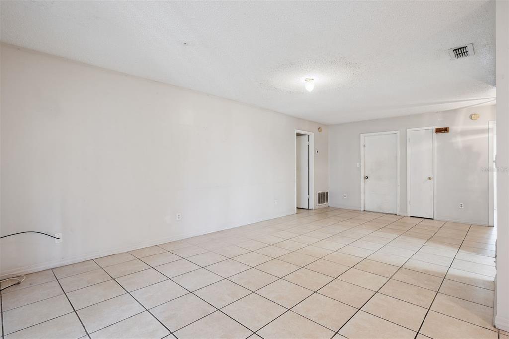 An empty room with light-colored tile flooring, white walls, and a central ceiling light fixture — 2163 DILL DRIVE, ORLANDO, FL