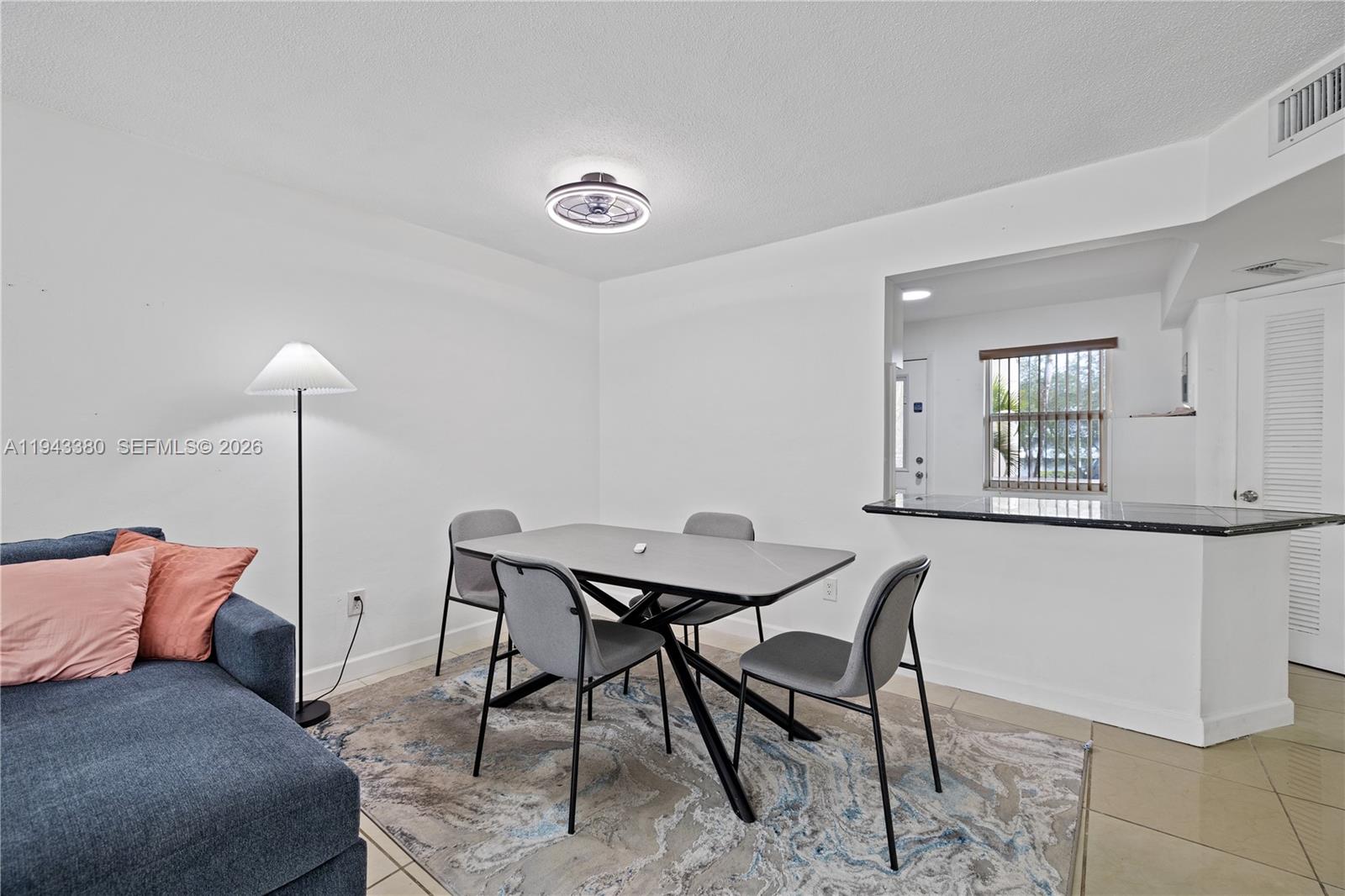 A dining area features a modern table, four gray chairs, and a patterned area rug — 1501 NE 191st St # C216, Miami FL 33179, MIAMI, FL