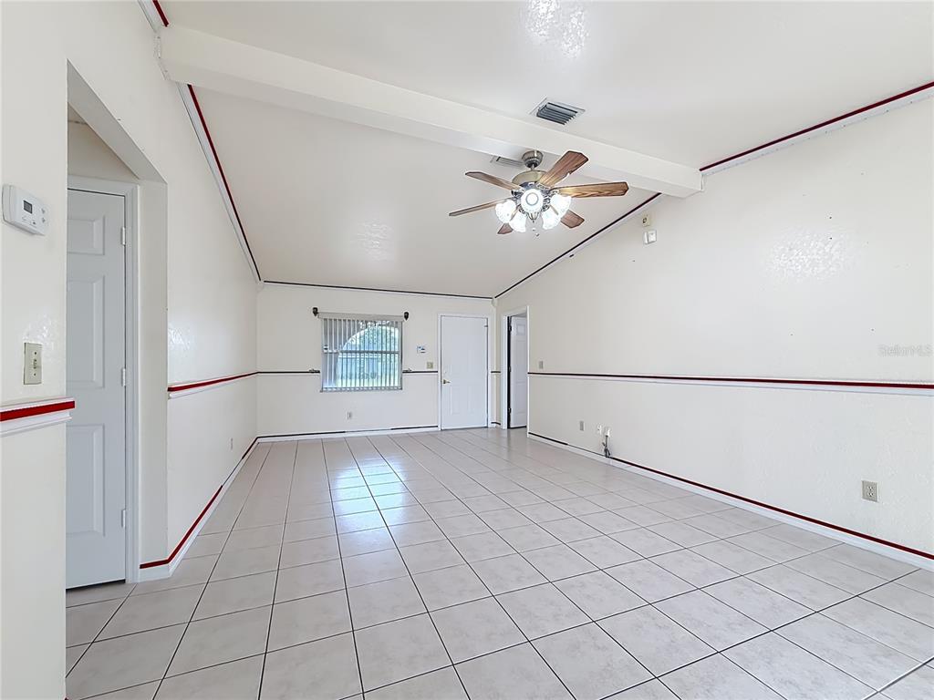 A spacious living room features white walls with red trim, tiled flooring, and a ceiling fan — 2939 SW 144TH PLACE ROAD, OCALA, FL