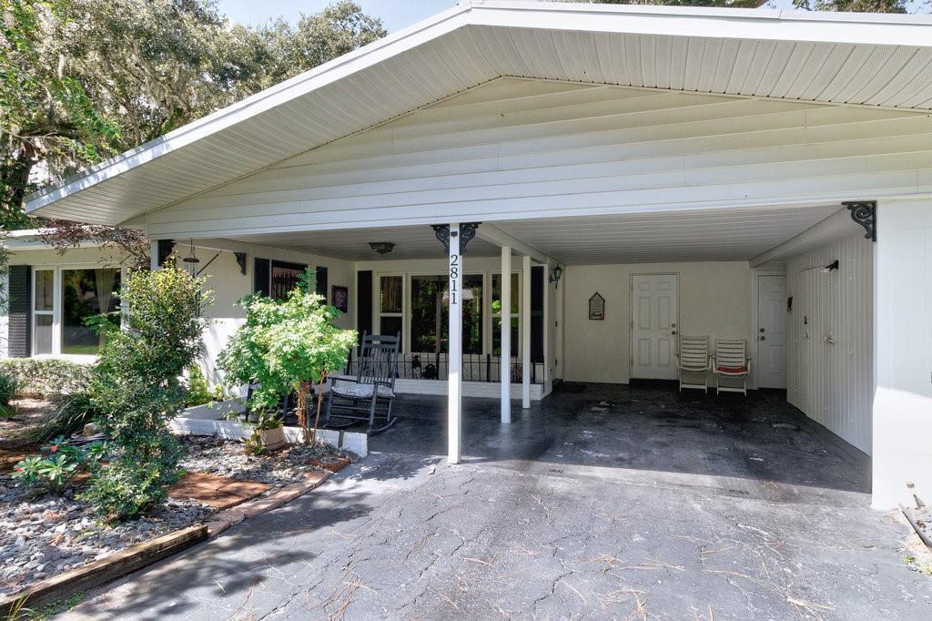 A white house exterior features a large carport, a front porch, and a paved driveway — 2811 10th Avenue, Vero Beach FL 32960, VERO BEACH, FL