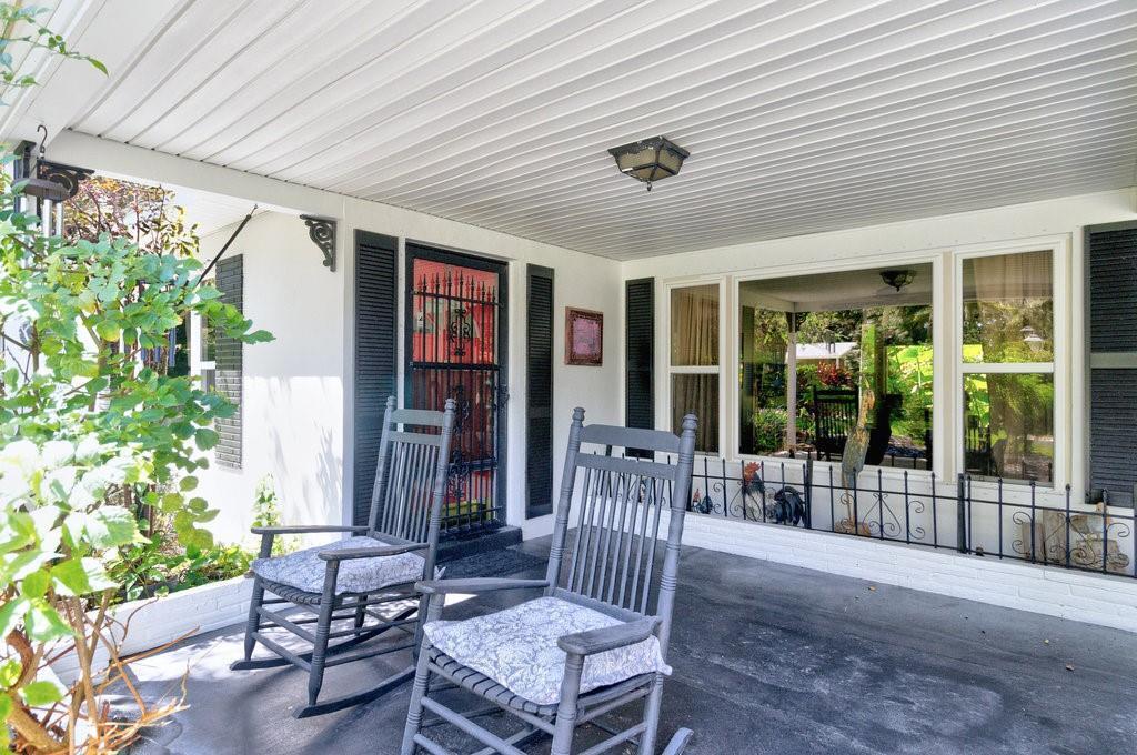 A covered front porch features two rocking chairs, a screen door, and large windows — 2811 10th Avenue, Vero Beach FL 32960, VERO BEACH, FL
