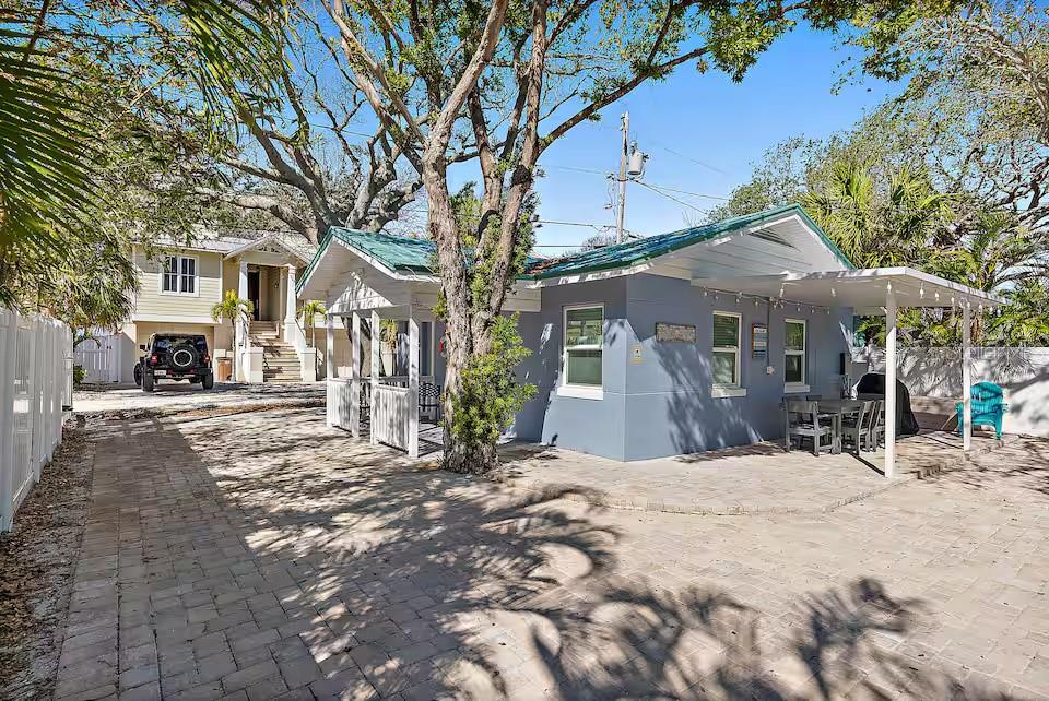 A blue house with a metal roof and a paved patio sits beside a driveway — 724 GULF BOULEVARD, INDIAN ROCKS BEACH, FL