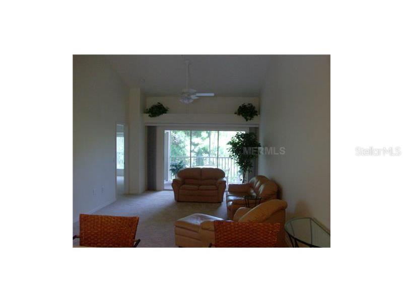 A living room features beige carpet, tan furniture, and a sliding glass door to a balcony — 4645 TOWER HILL LANE UNIT 2521, SARASOTA, FL