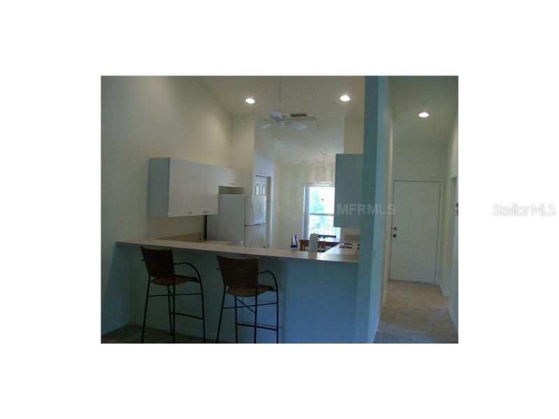 A kitchen with a breakfast bar, white cabinets, and a view into the dining area — 4645 TOWER HILL LANE UNIT 2521, SARASOTA, FL