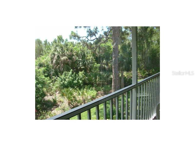 A view of a wooded area from a screened-in balcony with a metal railing — 4645 TOWER HILL LANE UNIT 2521, SARASOTA, FL