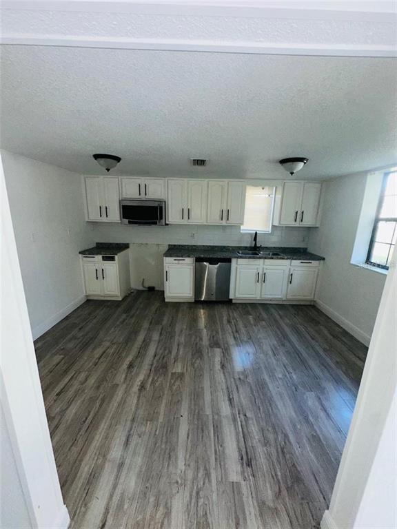 A kitchen features white cabinets, stainless steel appliances, and wood-look flooring — 10221 BEAM STREET, JACKSONVILLE, FL