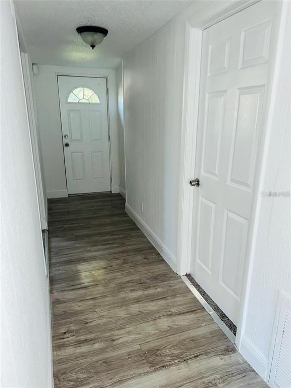 A hallway with white walls, wood-look flooring, a front door, and a closed interior door — 10221 BEAM STREET, JACKSONVILLE, FL