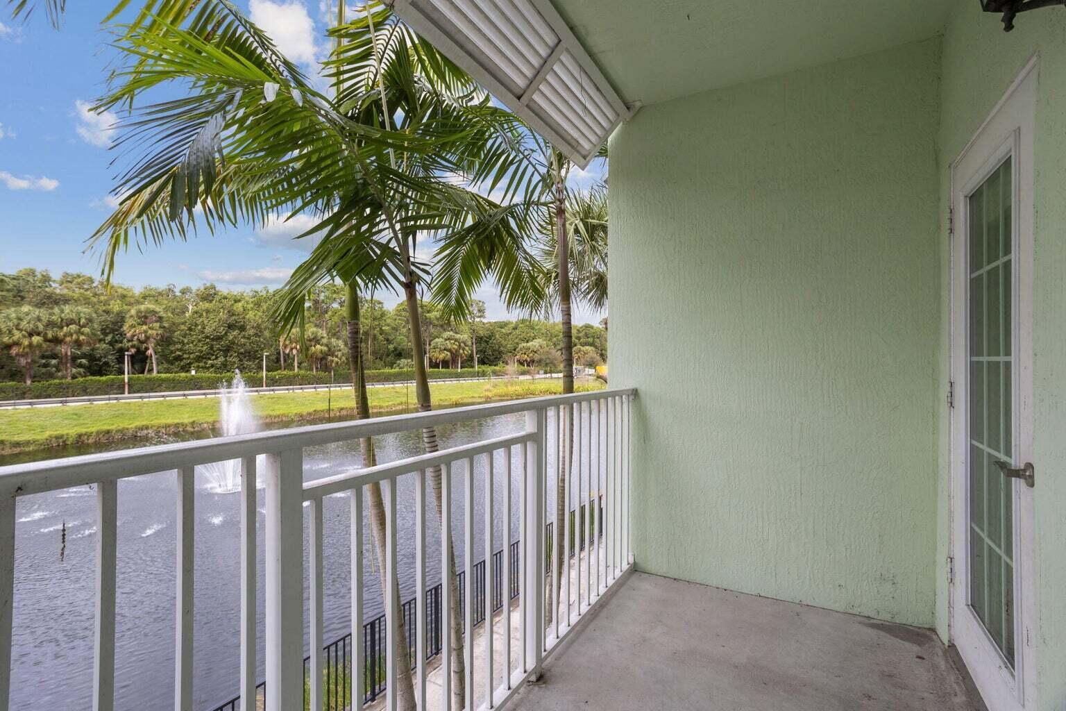 A balcony with a white railing overlooks a pond with a fountain and palm trees — 3617 High Ridge Way # 206, Boynton Beach FL 33426, BOYNTON BEACH, FL