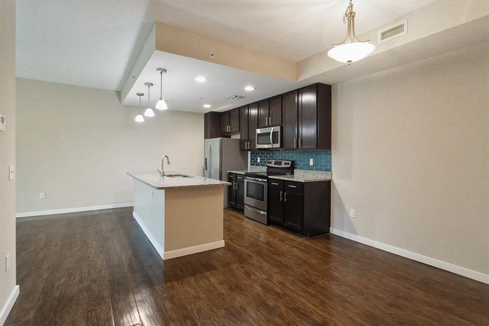 A kitchen features dark wood cabinets, stainless steel appliances, granite countertops, and a center island — 3617 High Ridge Way # 206, Boynton Beach FL 33426, BOYNTON BEACH, FL