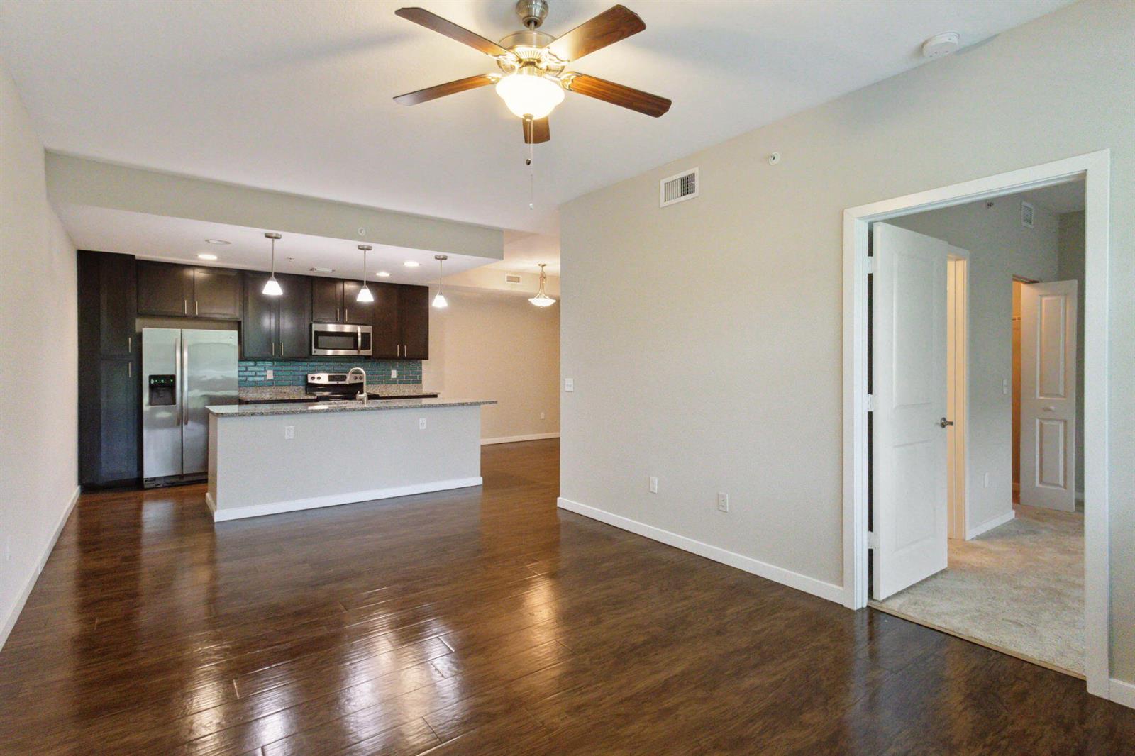 An open-concept living area features dark wood flooring, a kitchen with dark cabinets, and an entryway — 3617 High Ridge Way # 206, Boynton Beach FL 33426, BOYNTON BEACH, FL