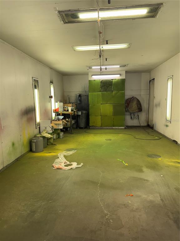 An industrial paint booth features a green filter wall, overhead lighting, and a concrete floor — 906 SHADICK DRIVE, ORANGE CITY, FL