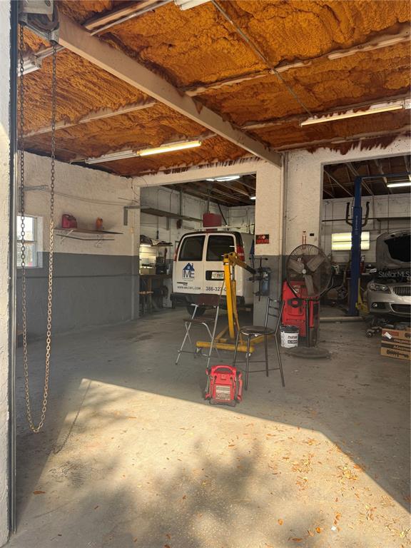A garage workshop features a spray-foam insulated ceiling, concrete floors, and an engine hoist — 906 SHADICK DRIVE, ORANGE CITY, FL