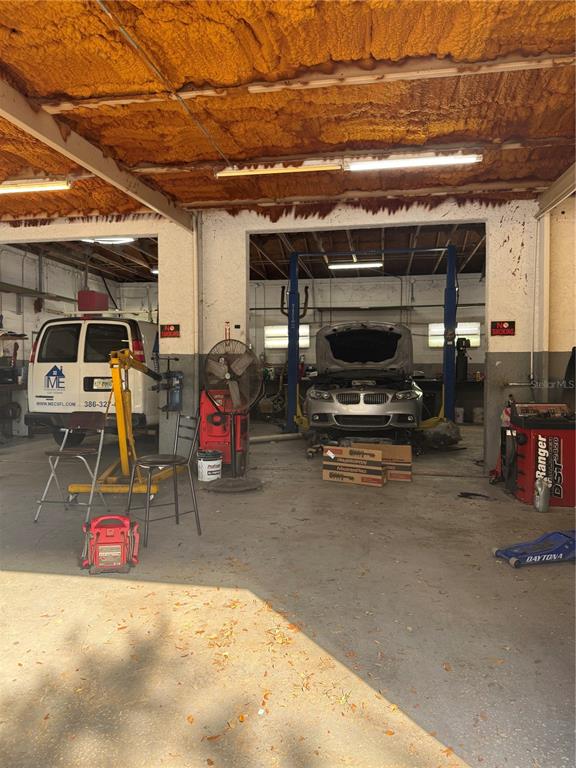 An automotive repair shop features two service bays, a vehicle lift, and exposed spray foam insulation — 906 SHADICK DRIVE, ORANGE CITY, FL