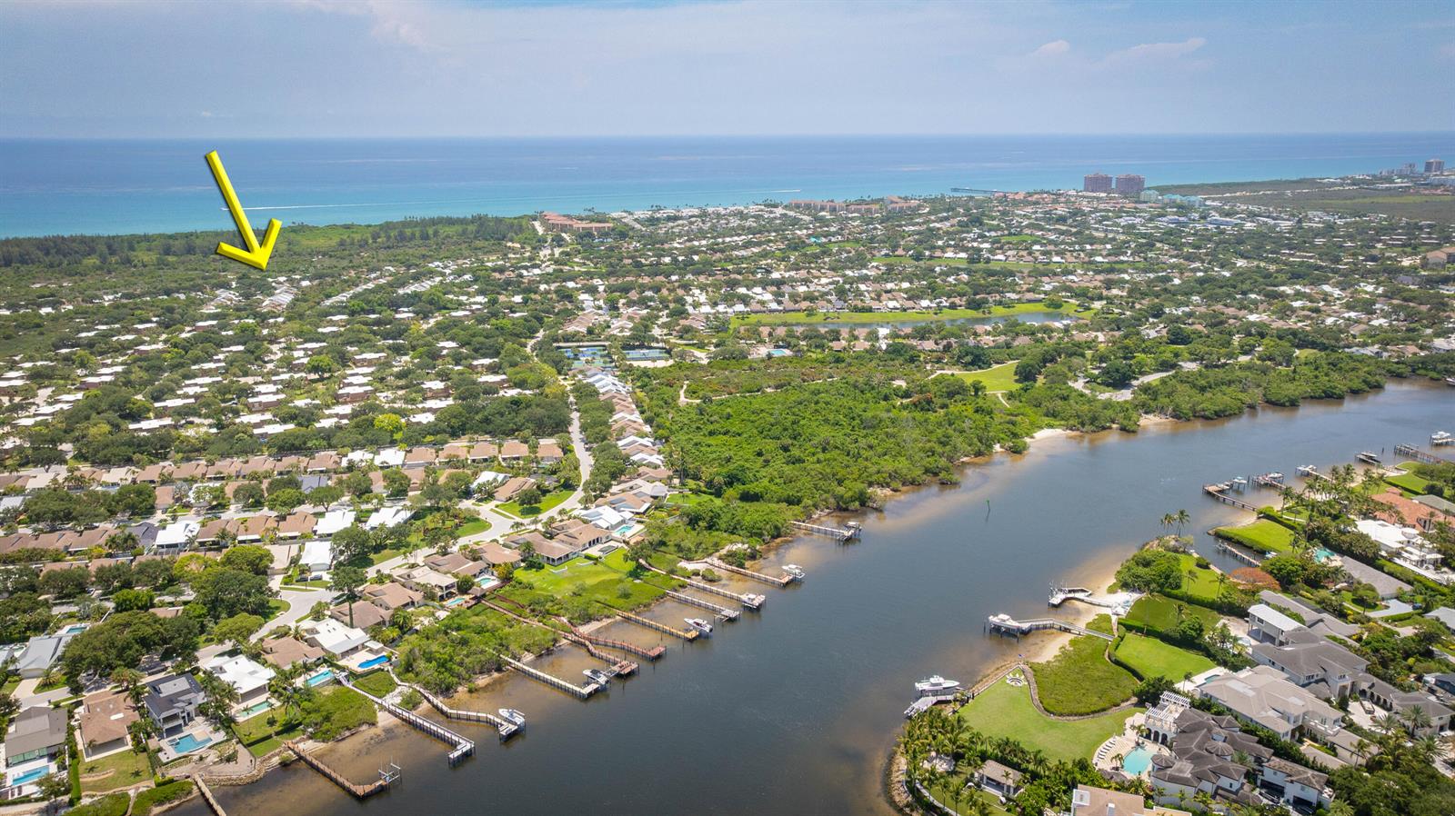 An aerial view shows a residential neighborhood with a canal, boat docks, and ocean views — 137 Seashore Drive, Jupiter FL 33477, JUPITER, FL