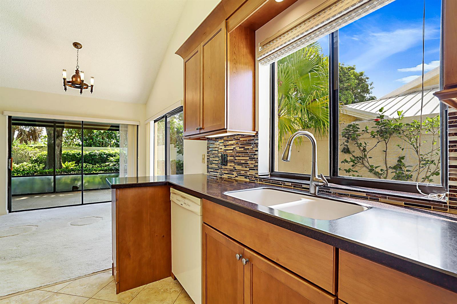 A kitchen with wood cabinets, dark countertops, a white sink, and a view of greenery — 137 Seashore Drive, Jupiter FL 33477, JUPITER, FL
