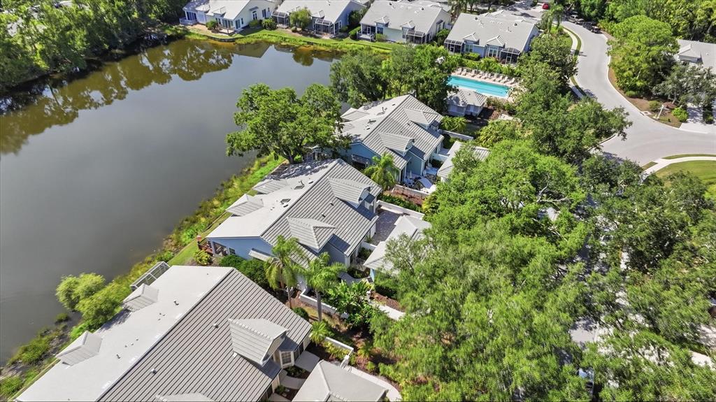An aerial view shows several houses with gray roofs situated along a lake — 7706 WHITEBRIDGE GLEN, UNIVERSITY PARK, FL